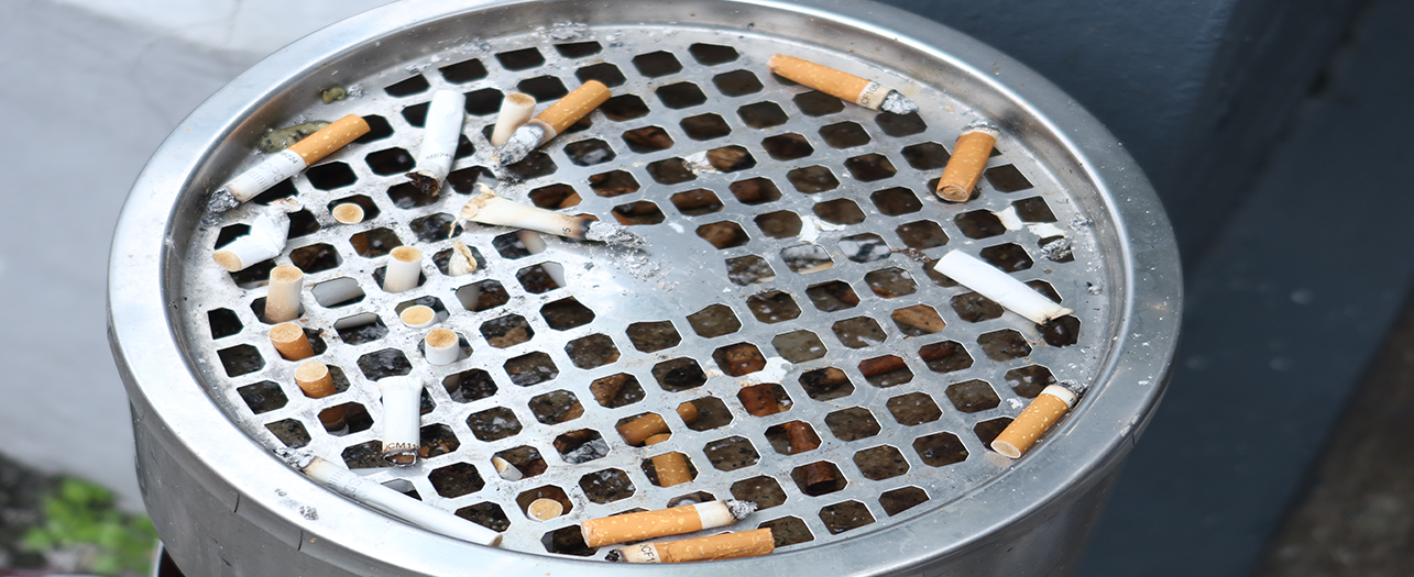 Outdoor metal ashtray bin filled with cigarette butts